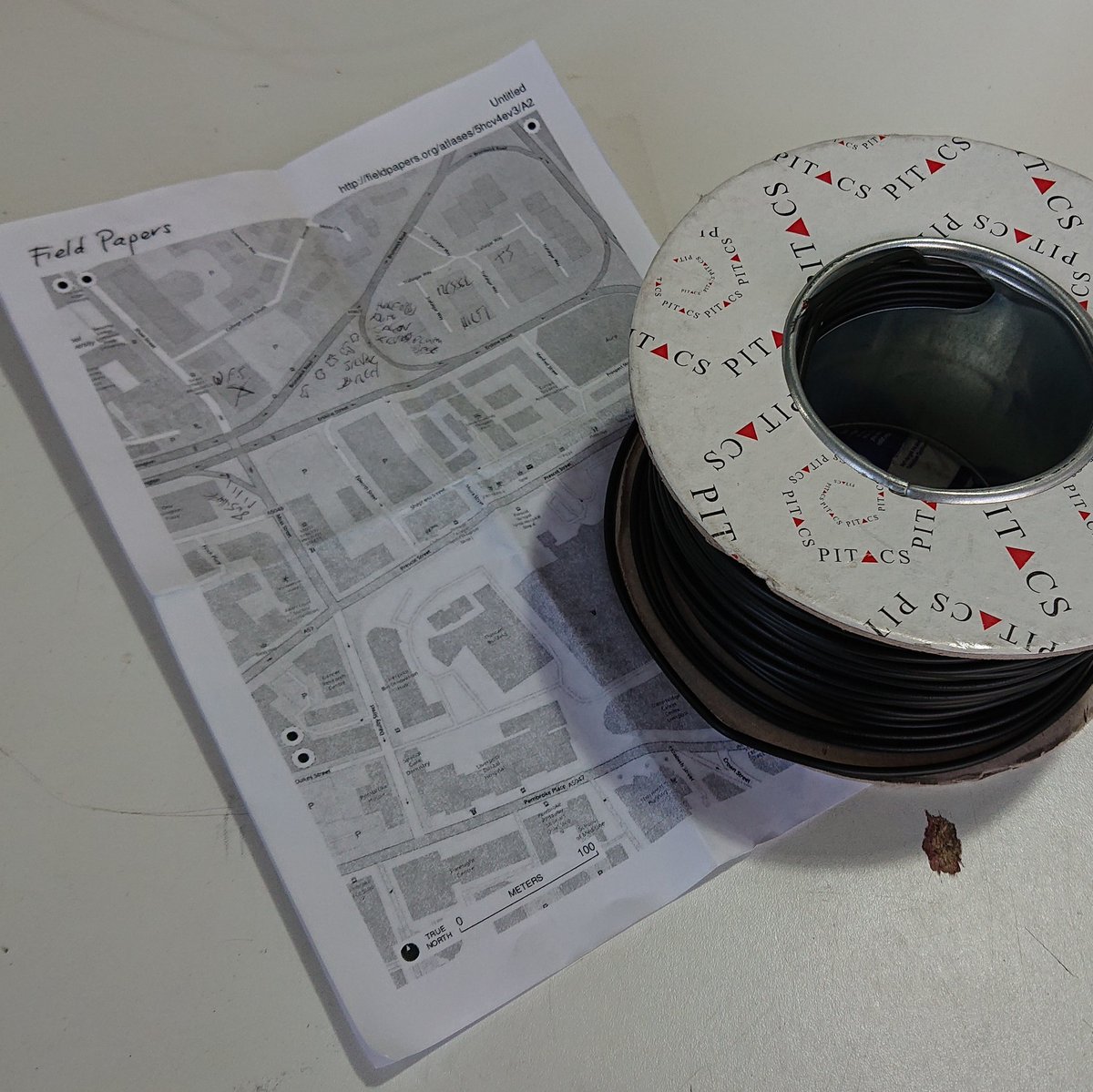 A reel of electrical wire, next to a print out of a map marked up with hand-written notes