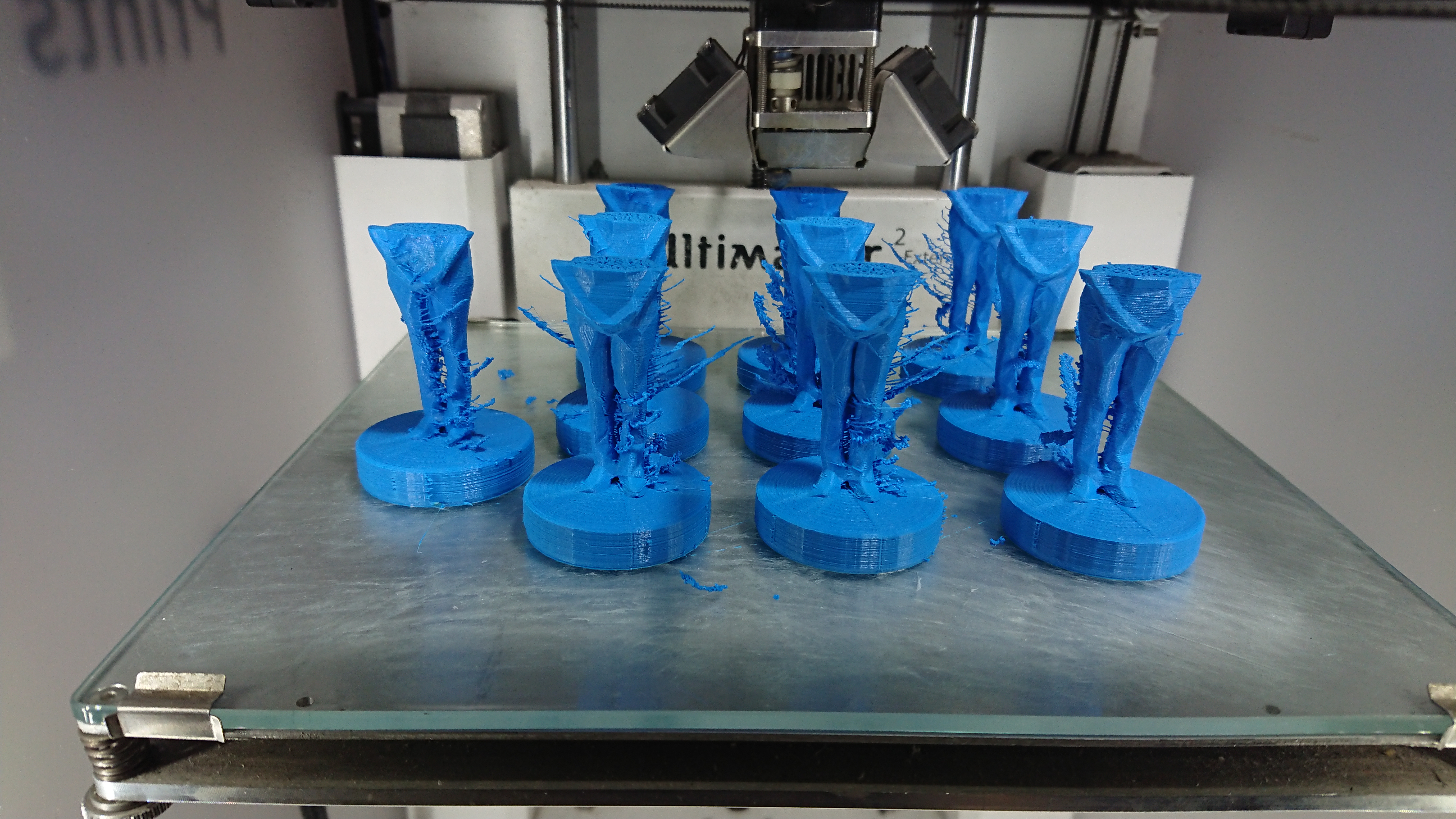 Ten blue figurines, in the middle of being 3D printed